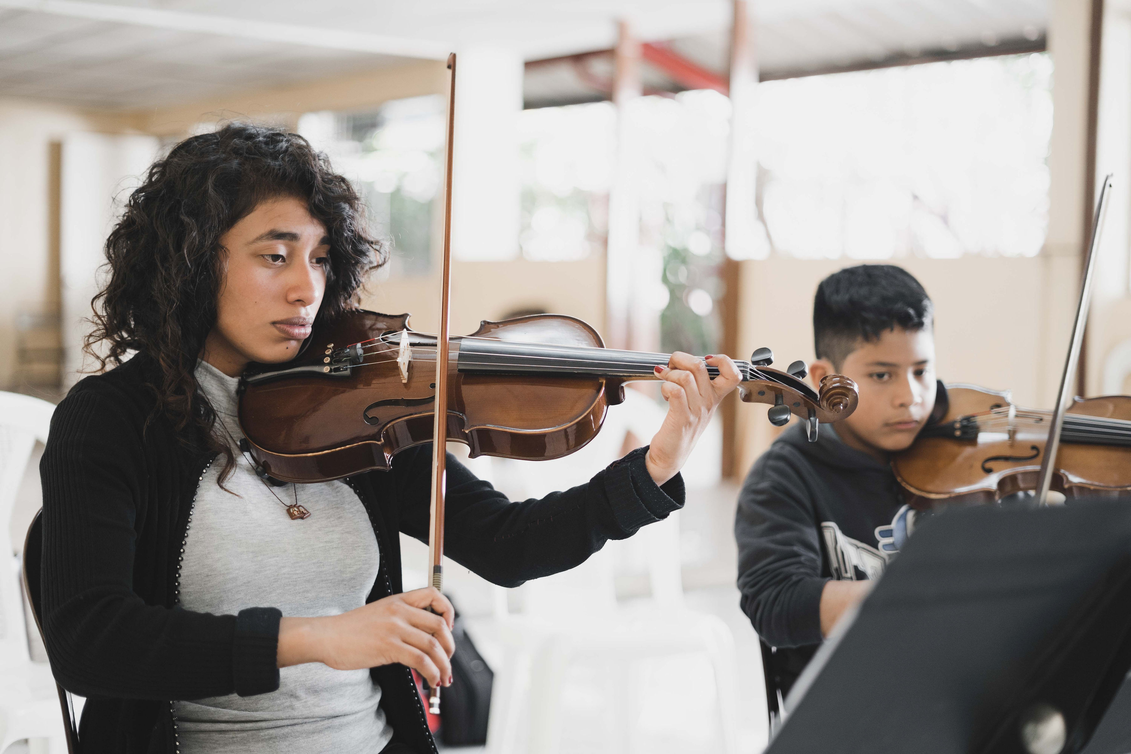 A mentor and student playing violin together