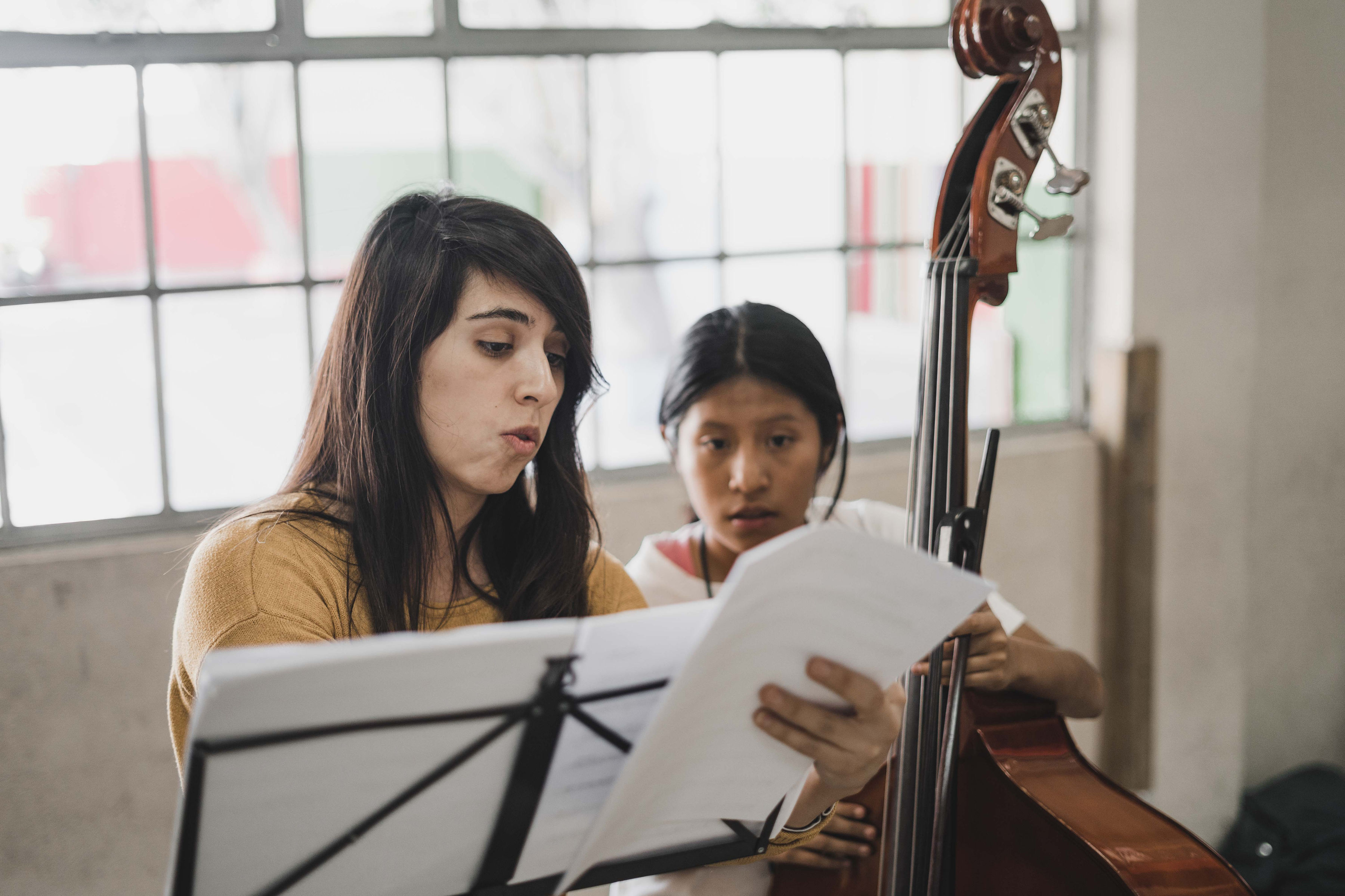 A teaching artist reading music with a student at the double bass