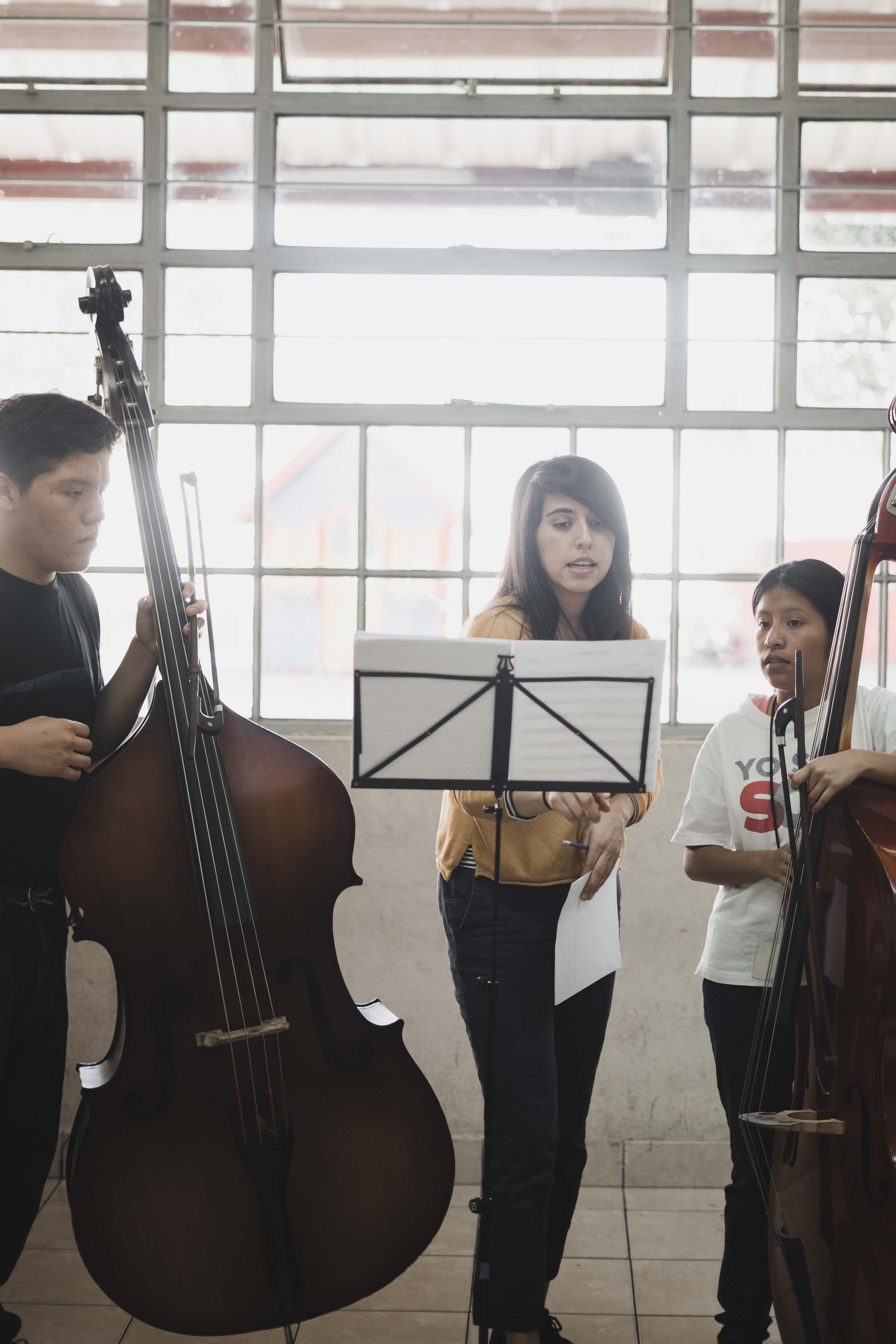 A teaching artist guiding bass students in rehearsal